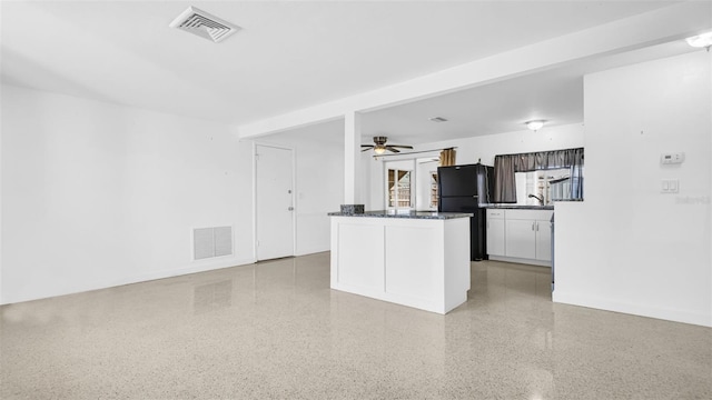 kitchen featuring ceiling fan, white cabinets, and black fridge