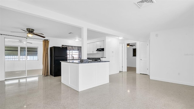 kitchen with black refrigerator, dark stone countertops, white cabinets, and ceiling fan