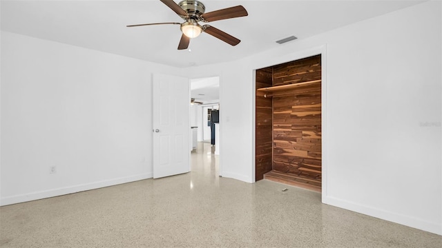 unfurnished room featuring ceiling fan and wood walls