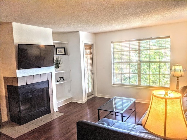 living room featuring dark hardwood / wood-style flooring, a textured ceiling, and a tiled fireplace