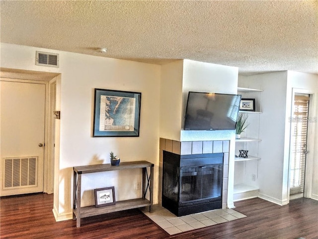 unfurnished living room with a tile fireplace, wood-type flooring, and a textured ceiling