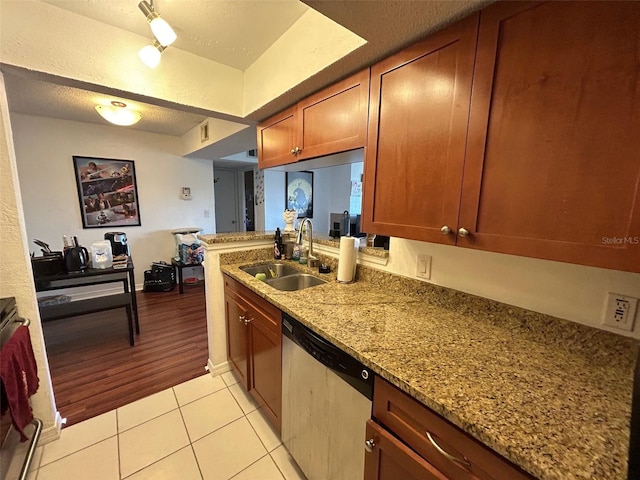 kitchen featuring light stone countertops, stainless steel dishwasher, a textured ceiling, sink, and light hardwood / wood-style flooring