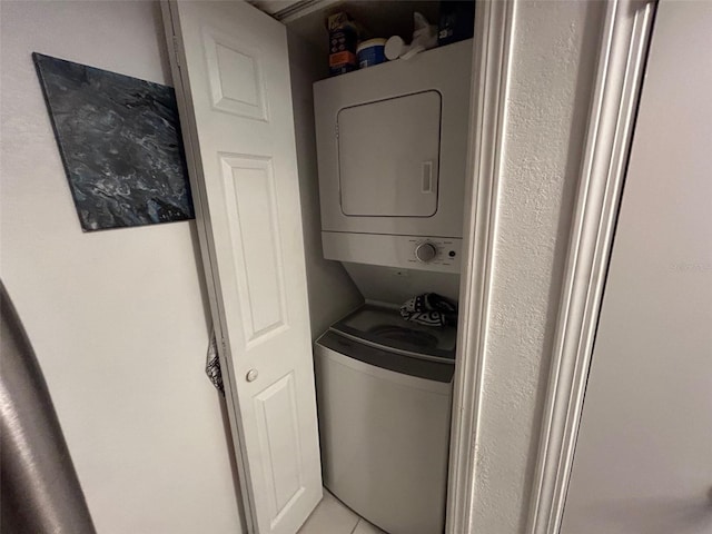 clothes washing area featuring light tile patterned floors and stacked washing maching and dryer