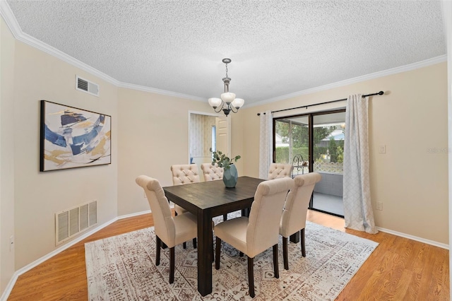 dining area featuring light hardwood / wood-style floors, crown molding, a textured ceiling, and an inviting chandelier