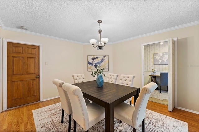 dining room with a textured ceiling, an inviting chandelier, light hardwood / wood-style flooring, and ornamental molding