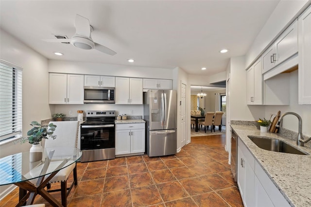 kitchen with light stone countertops, white cabinetry, sink, ceiling fan, and stainless steel appliances