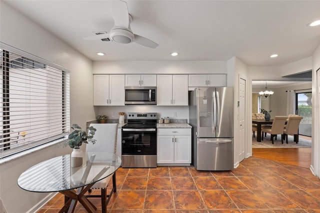 kitchen with ceiling fan with notable chandelier, white cabinetry, stainless steel appliances, and decorative light fixtures