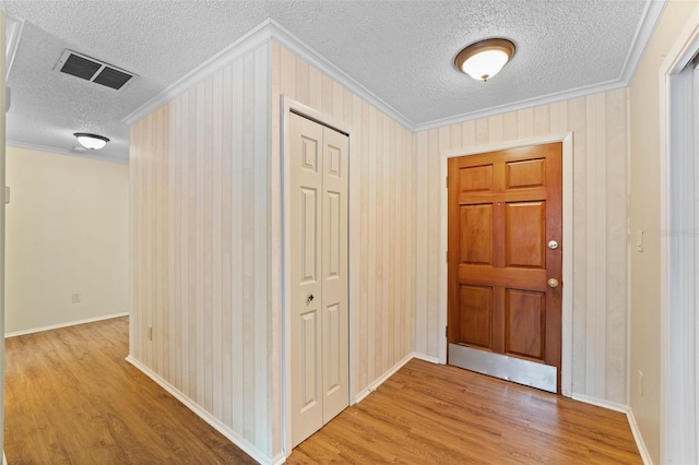 foyer entrance with crown molding, a textured ceiling, and light wood-type flooring