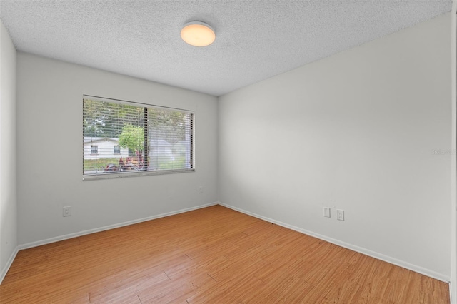 empty room with a textured ceiling and light wood-type flooring