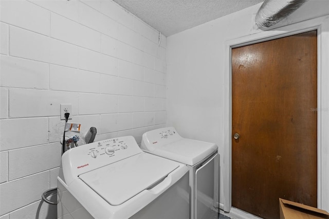 laundry area featuring a textured ceiling and washing machine and clothes dryer