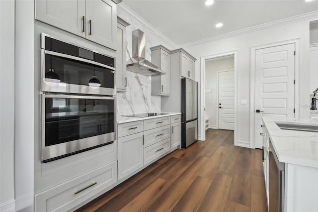 kitchen with wall chimney range hood, decorative backsplash, light stone countertops, appliances with stainless steel finishes, and dark hardwood / wood-style flooring