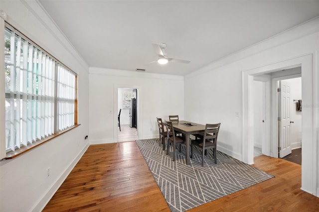 dining area with ceiling fan, a healthy amount of sunlight, wood-type flooring, and crown molding