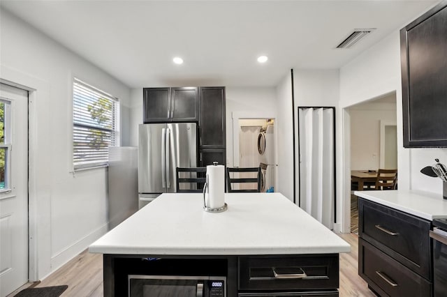 kitchen with light wood-type flooring, stainless steel appliances, and a kitchen island