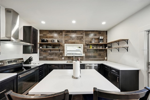 kitchen featuring appliances with stainless steel finishes, sink, tasteful backsplash, and wall chimney range hood