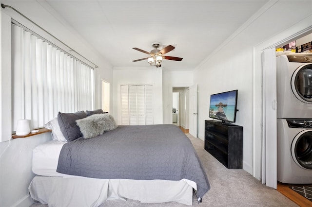 bedroom with carpet, ornamental molding, ceiling fan, and stacked washer and clothes dryer