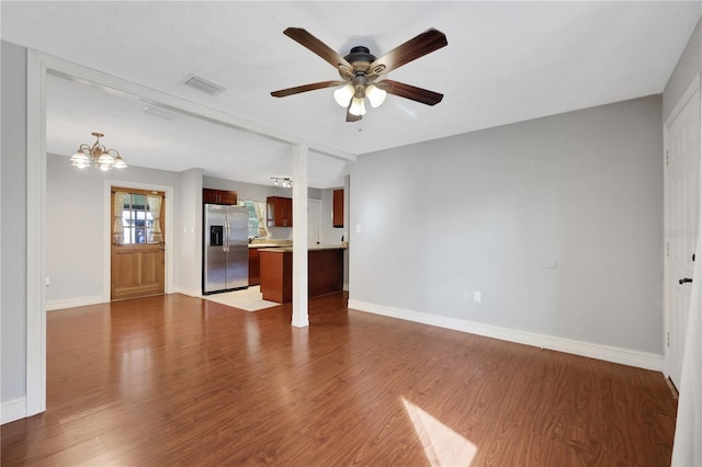 unfurnished living room featuring ceiling fan with notable chandelier and hardwood / wood-style floors