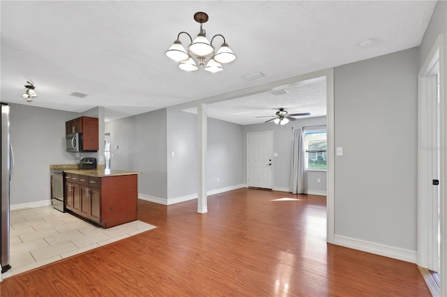 kitchen featuring ceiling fan with notable chandelier, light hardwood / wood-style flooring, appliances with stainless steel finishes, and a textured ceiling