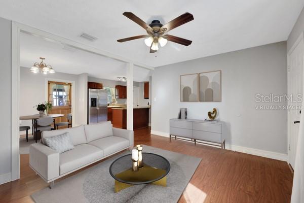 living room with ceiling fan with notable chandelier and dark hardwood / wood-style flooring