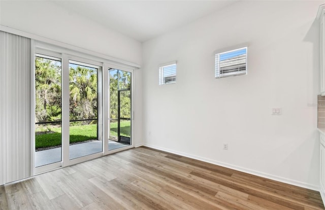 spare room featuring baseboards and light wood-style floors