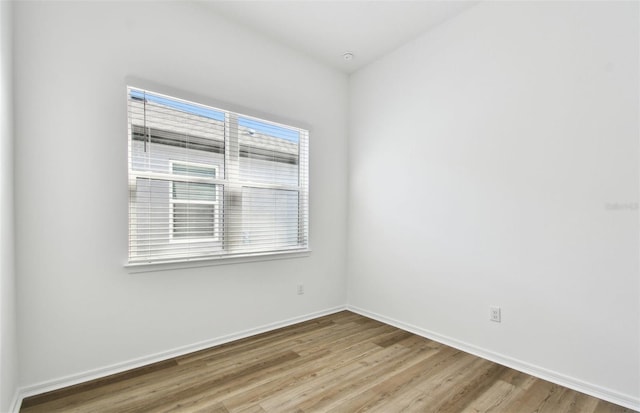 spare room with baseboards and wood finished floors