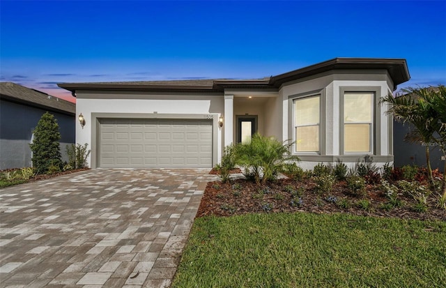 view of front facade featuring a garage, decorative driveway, and stucco siding