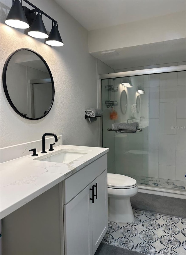 bathroom featuring tile patterned flooring, vanity, toilet, and a shower with shower door