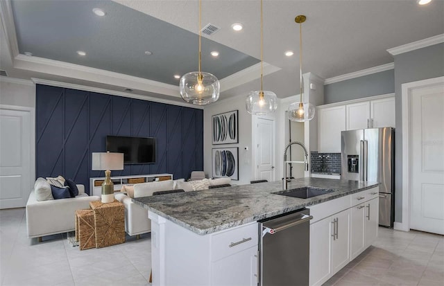 kitchen with white cabinetry, sink, stainless steel appliances, a kitchen island with sink, and ornamental molding