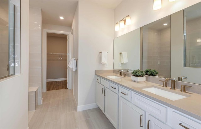 bathroom with a tile shower, tile patterned flooring, and vanity