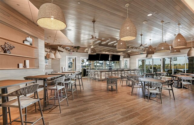 dining space with wood-type flooring, ceiling fan, wooden walls, and wood ceiling