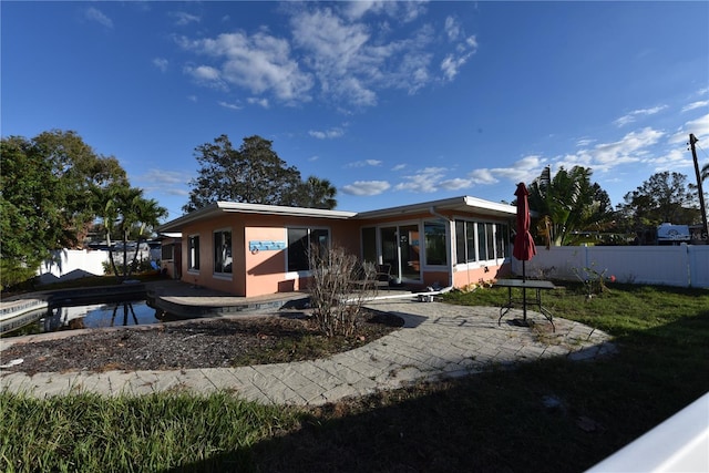 back of house featuring a patio area, fence, a sunroom, and stucco siding