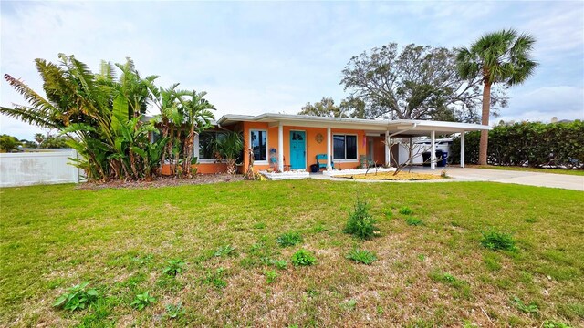 view of front of property featuring a carport, driveway, a front lawn, and stucco siding