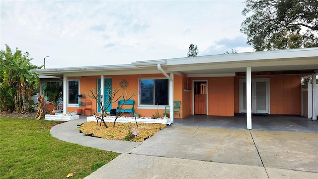 ranch-style home with a carport, driveway, and a front lawn