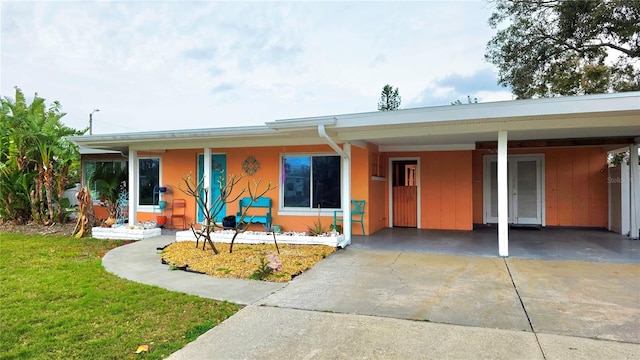 ranch-style house featuring a front lawn, a carport, and concrete driveway