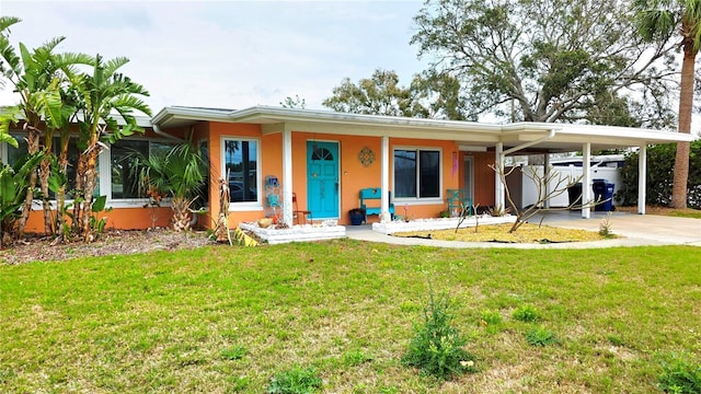 view of front of property with a carport, a front yard, concrete driveway, and stucco siding