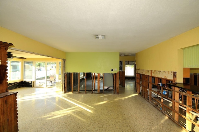 interior space featuring visible vents, ceiling fan, a textured ceiling, and speckled floor