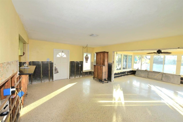 kitchen with dark countertops, brown cabinets, hanging light fixtures, and speckled floor