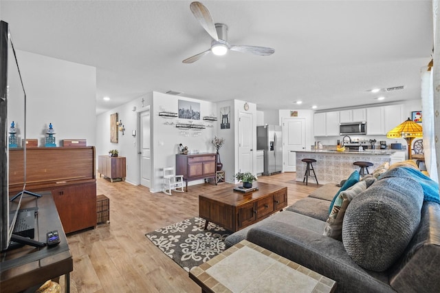 living room featuring light hardwood / wood-style flooring and ceiling fan