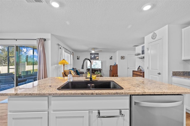 kitchen featuring a healthy amount of sunlight, sink, white cabinetry, and a textured ceiling