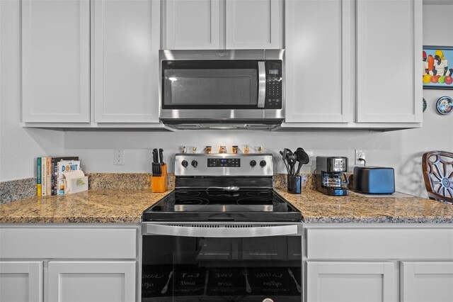 kitchen with light stone counters, white cabinetry, and appliances with stainless steel finishes