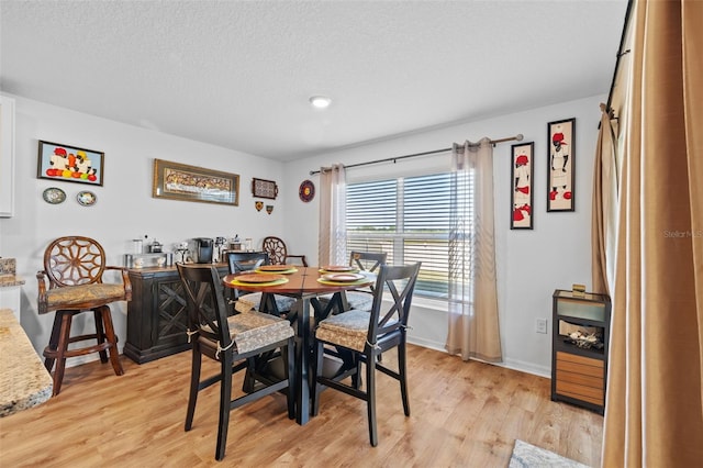 dining area with a textured ceiling and light hardwood / wood-style floors