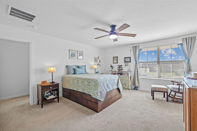 bedroom featuring light carpet, a textured ceiling, and ceiling fan