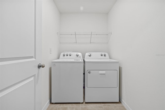 clothes washing area featuring washer and clothes dryer and light tile patterned flooring