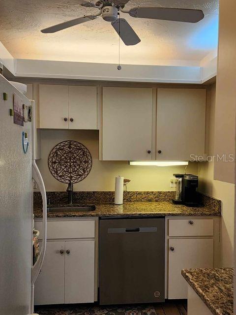 4632 Red Maple Rd Unit 1204, Bradenton, FL 34210 - kitchen featuring appliances with stainless steel finishes, a ceiling fan, a sink, white cabinetry, and dark stone counters