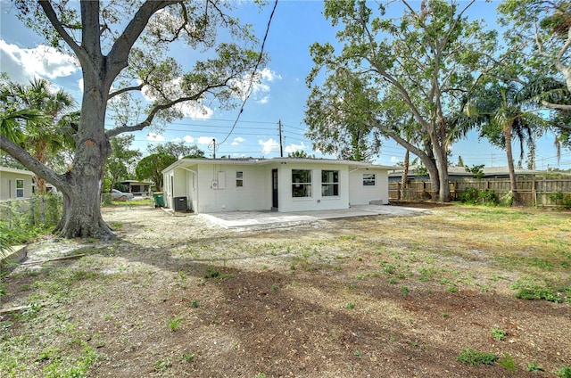 back of property with central air condition unit, a patio area, and a yard