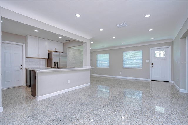 kitchen featuring white cabinets, backsplash, a center island, and stainless steel refrigerator with ice dispenser