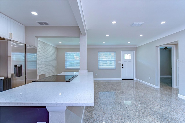 kitchen with stainless steel fridge, white cabinetry, and light stone countertops