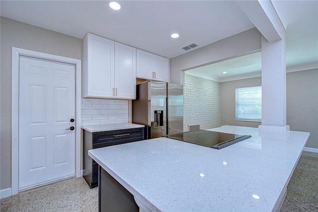 kitchen featuring black electric stovetop, tasteful backsplash, light stone counters, white cabinets, and stainless steel fridge with ice dispenser