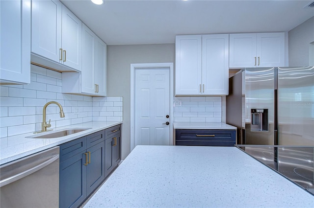 kitchen featuring white cabinets, stainless steel appliances, tasteful backsplash, and sink