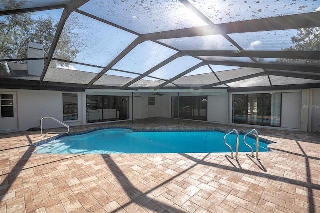 view of swimming pool featuring glass enclosure and a patio