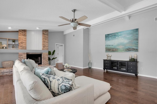 living room with ceiling fan, lofted ceiling with beams, a brick fireplace, and a textured ceiling